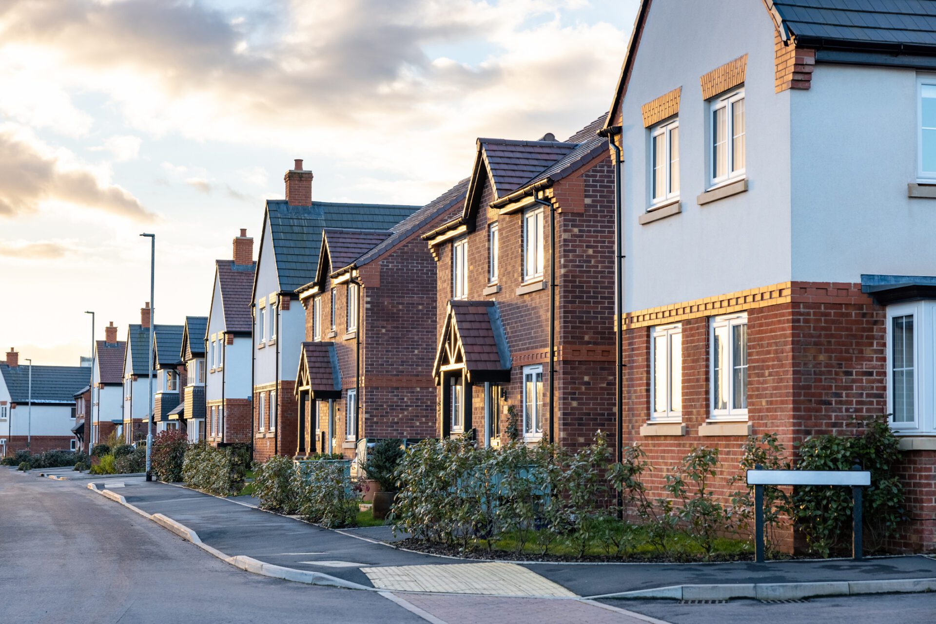 Houses in England with typical red bricks at sunset - Main street in a new estate with typical British houses on the side - Real estate and buildings concepts in UK UK residential property for home survey